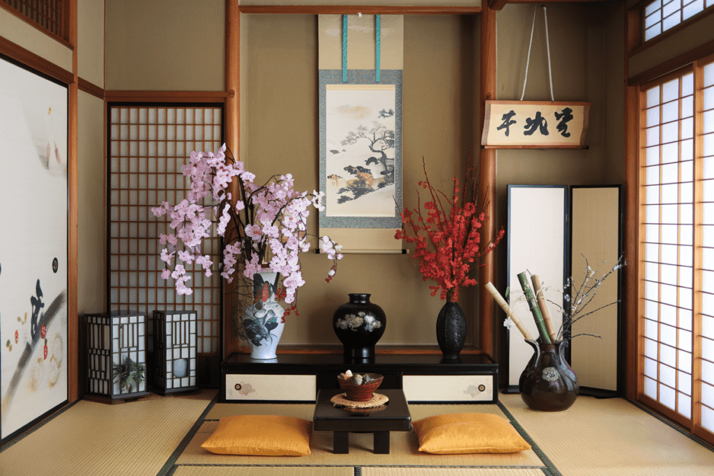A photo of a Japanese home interior with tatami mats
and a low wooden table. There are potted plants, a scroll painting, and a lantern on the table.